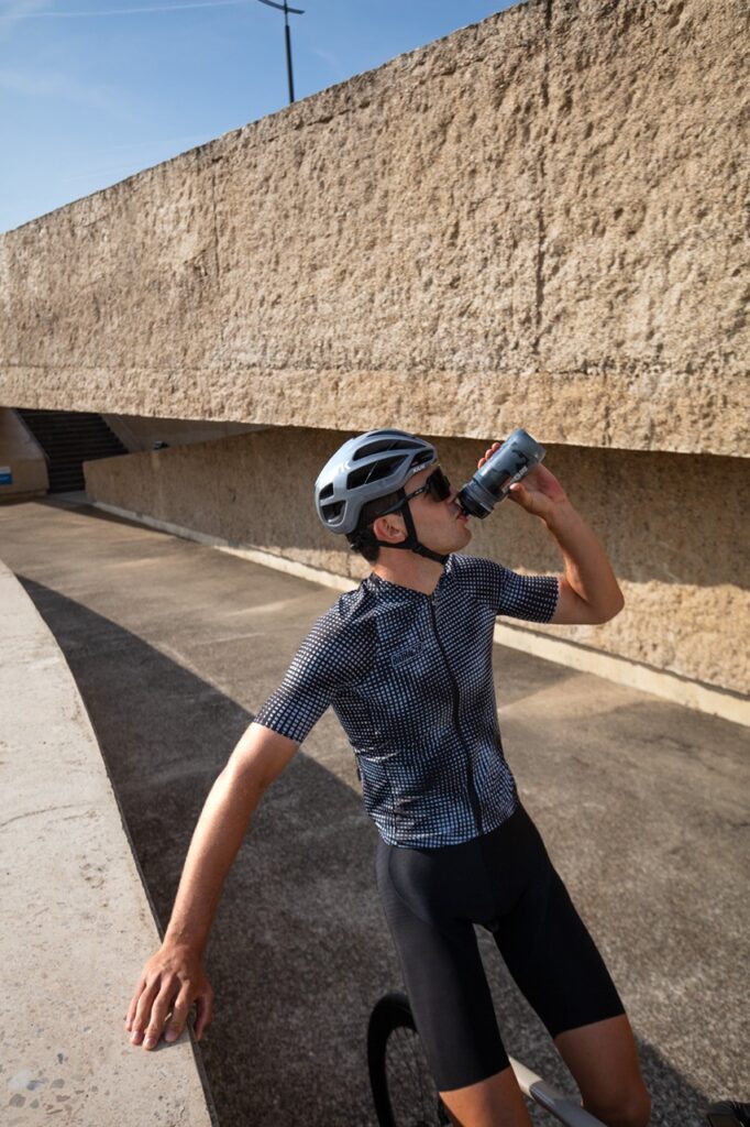 ciclista dando un sorbo a su bidón, vestido con ropa ciclista de bioracer